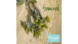 A cluster of green seaweed with bulbous tips lies on wet sand, capturing the essence of Seaweed Goodness. The word Seaweed is written in green above, with a small blue logo reading Therapist in the bottom right corner.
